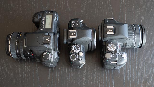 Olympus E-410 next to a Canon EOS 20D and Olympus E-500 cameras.